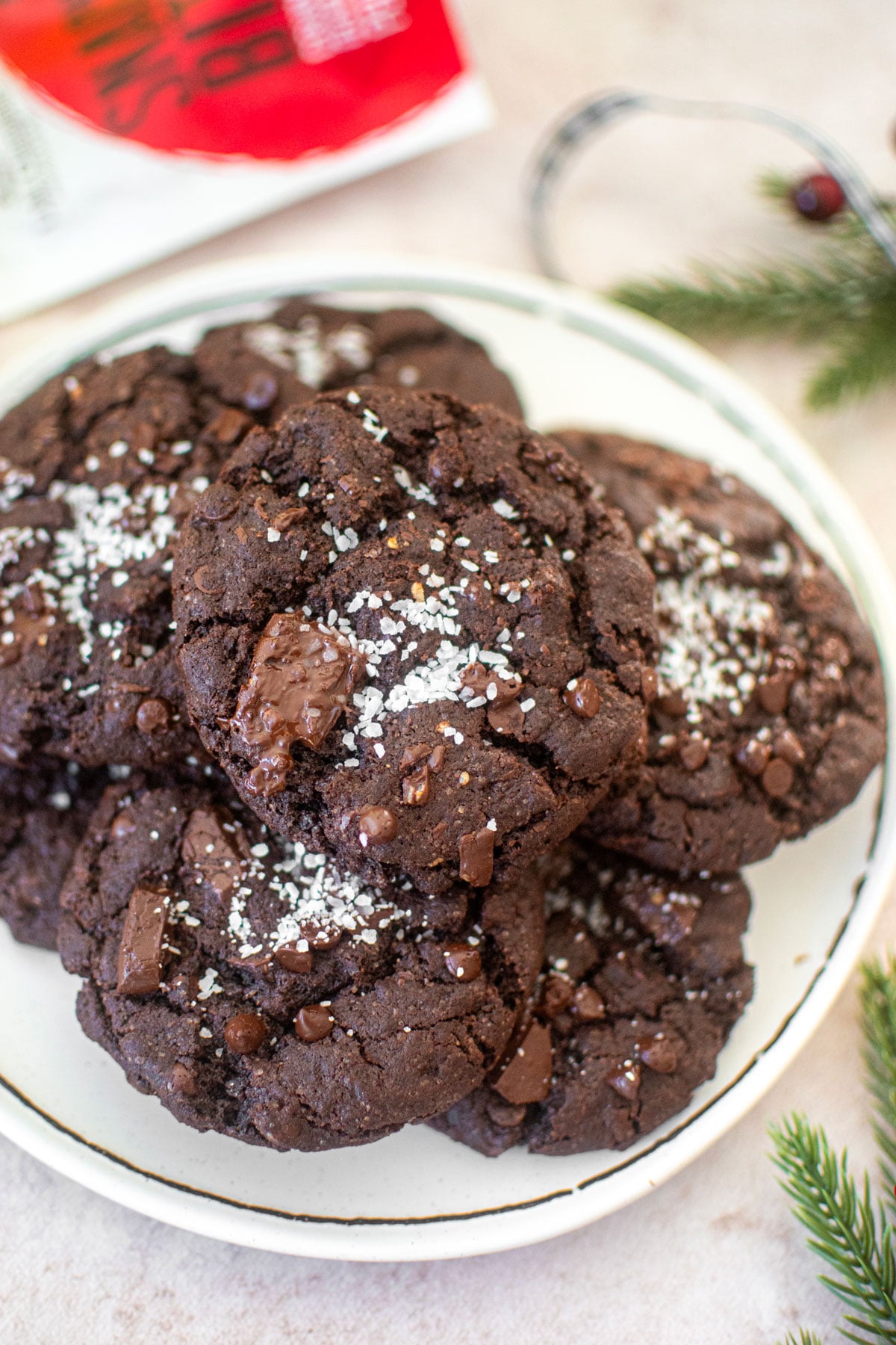 chocolate peppermint crunch cookies on a white plate with candy canes and festive greens around.