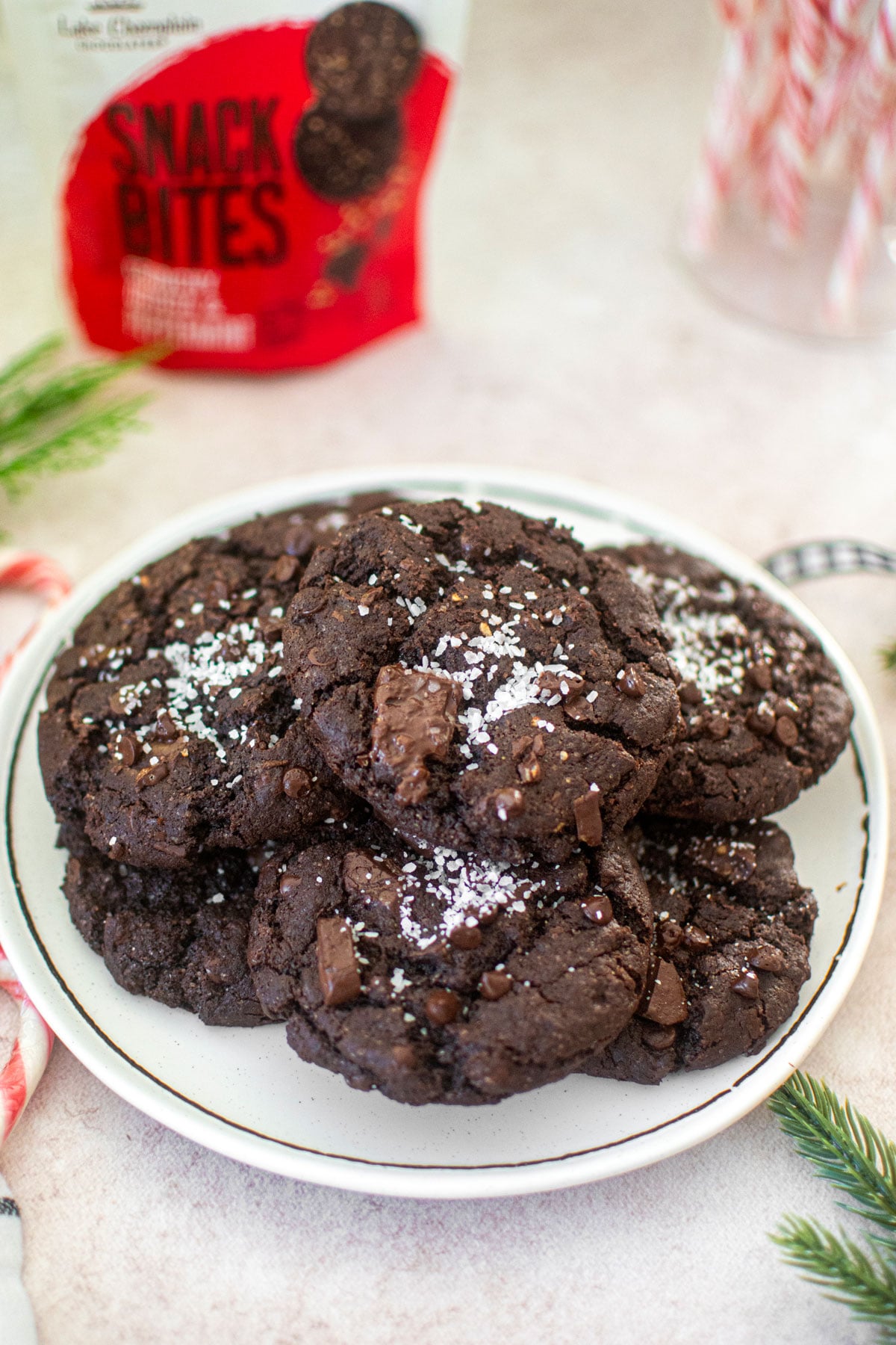 chocolate peppermint crunch cookies on a white plate with candy canes and festive greens around.