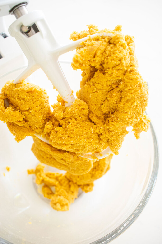 eggless brown sugar pumpkin cookie dough in a glass mixing bowl on a white marble counter.