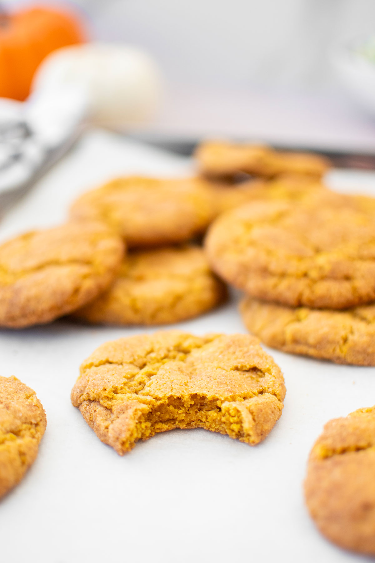 eggless brown sugar snickerdoodle cookies on a baking sheet, one with a bite taken out.