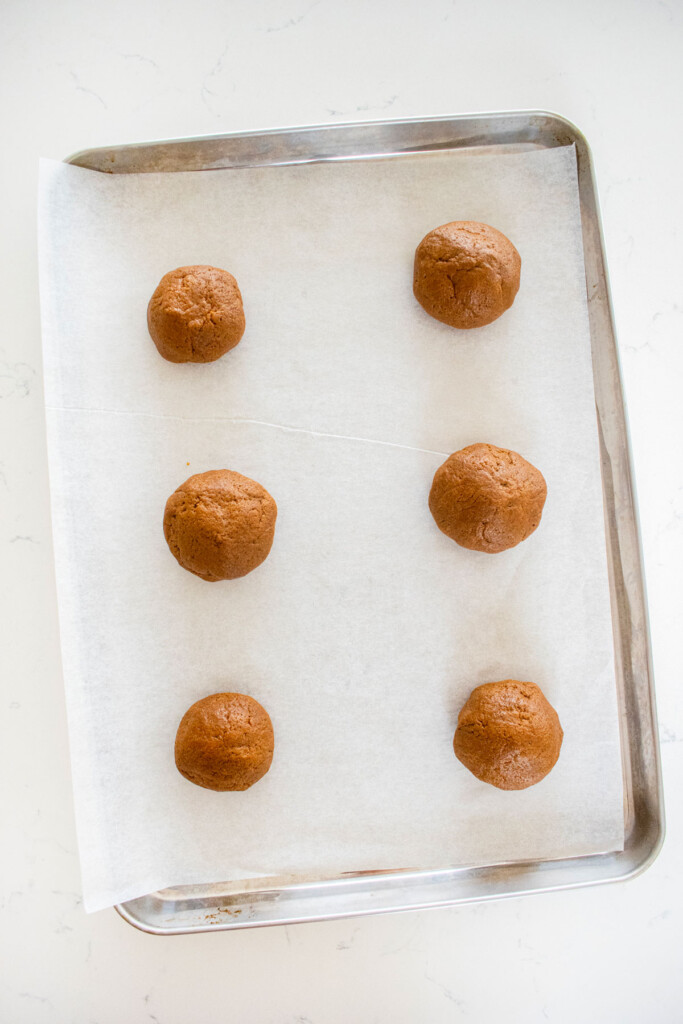 eggless pumpkin chocolate chip cookie dough balls on a baking sheet on a marble counter.
