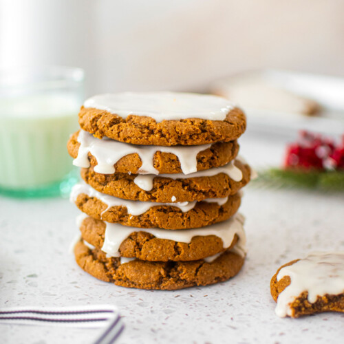 stack of eggless pumpkin gingerbread cookies on a marble counter with a glass of milk.