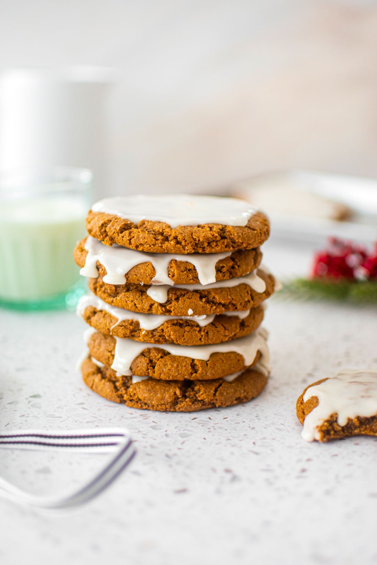 stack of eggless pumpkin gingerbread cookies on a marble counter with a glass of milk.