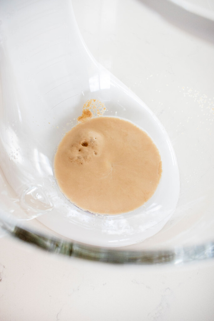 yeast in a glass mixing bowl on a white marble counter.