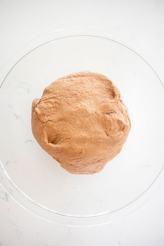 hot chocolate sweet roll dough in a glass mixing bowl on a white marble counter.