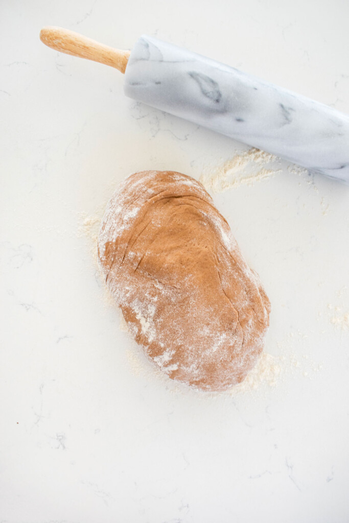 hot chocolate sweet roll dough on a white marble counter with a rolling pin.