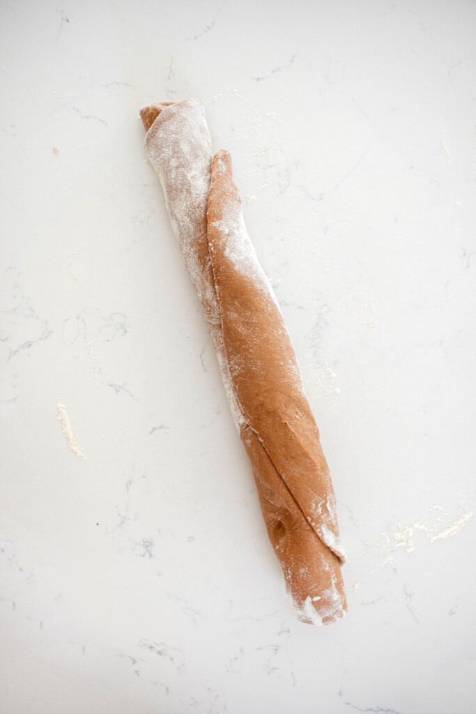 rolled hot chocolate sweet roll dough on a white marble counter.