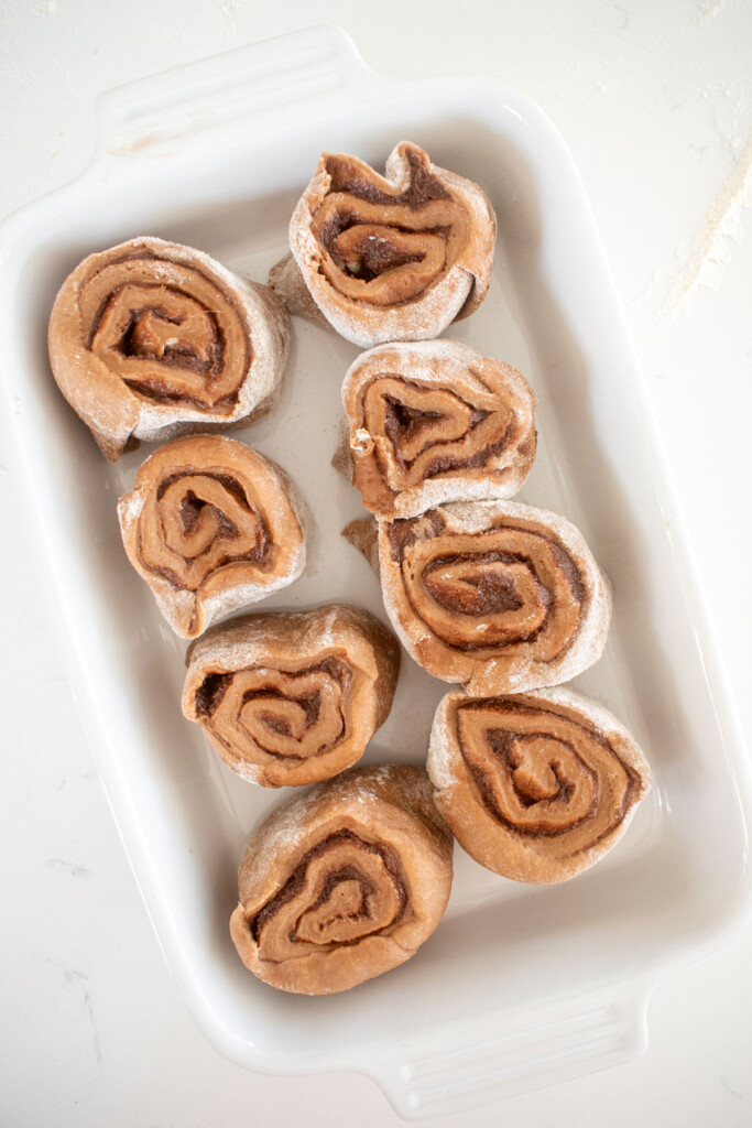 raw hot chocolate sweet rolls in a white baking dish on a marble counter.