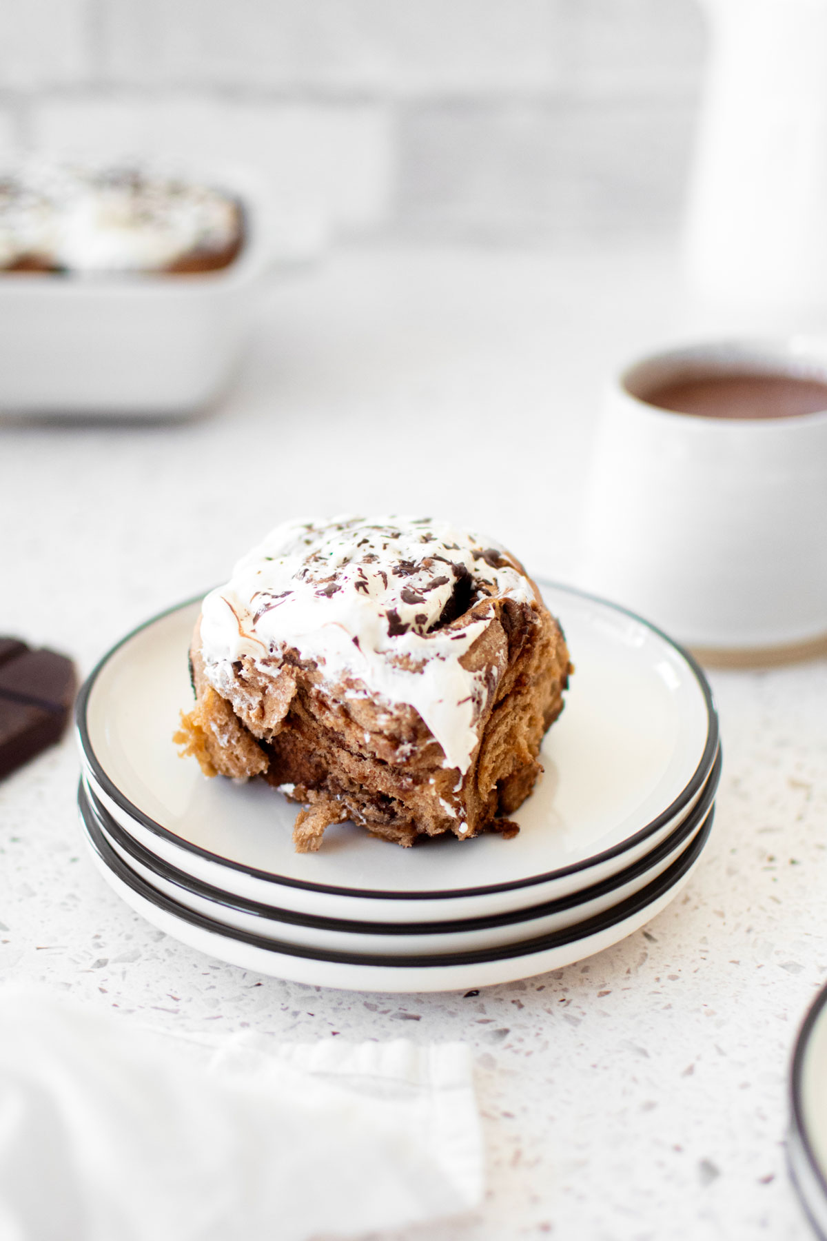 hot chocolate sweet roll on a stack of plates on a white stone counter.