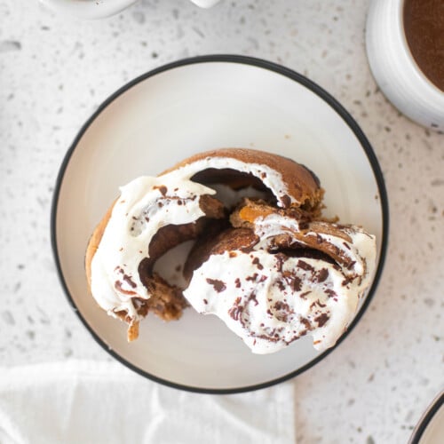 hot chocolate sweet roll on a white plate on a marble counter.