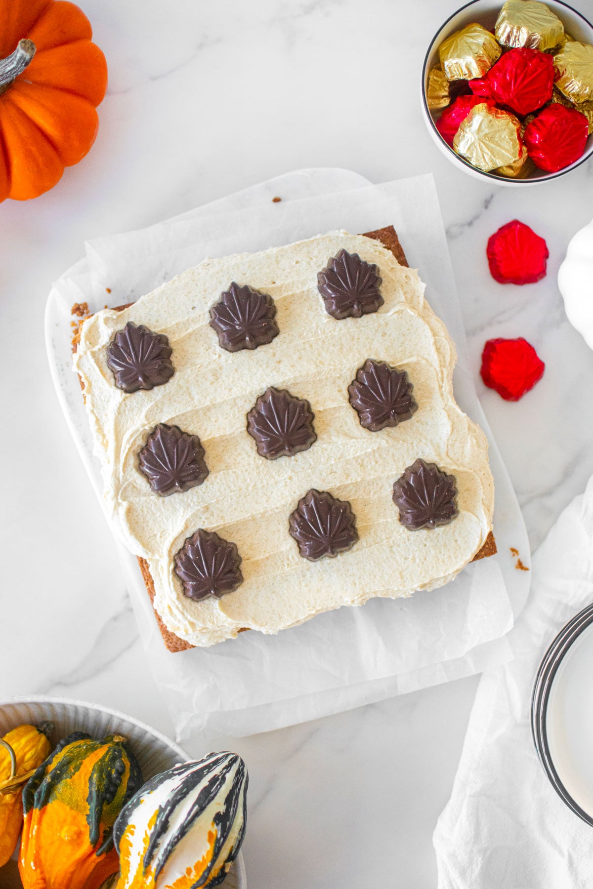 maple spice cake on a white marble board with pumpkins and maple leaves around.
