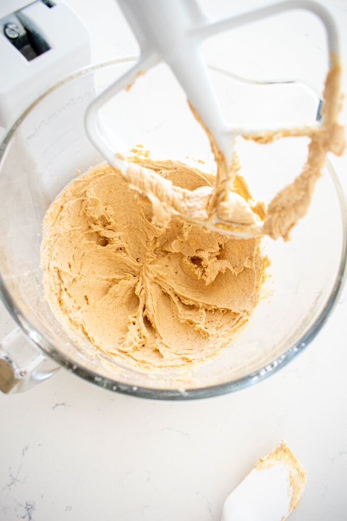 brown sugar frosting in a glass mixing bowl on a marble counter.