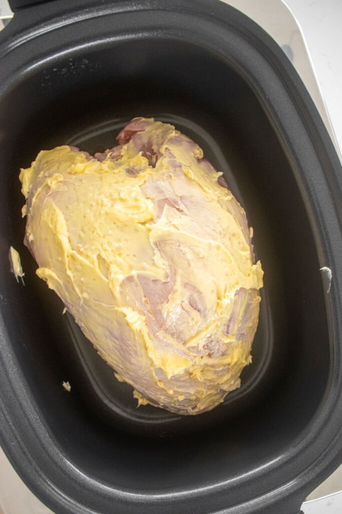 bone in turkey breast in a slow cooker with butter rubbed on it.