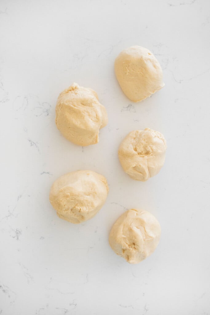 sourdough crescent roll dough balls on a white marble counter.