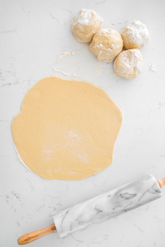 sourdough crescent roll dough on a baking sheet on a marble counter.