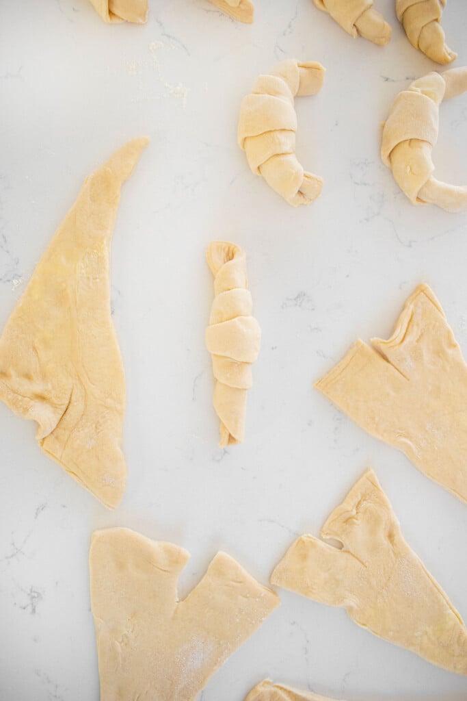 sourdough crescent rolls rolled into the crescent shape on a white marble counter.