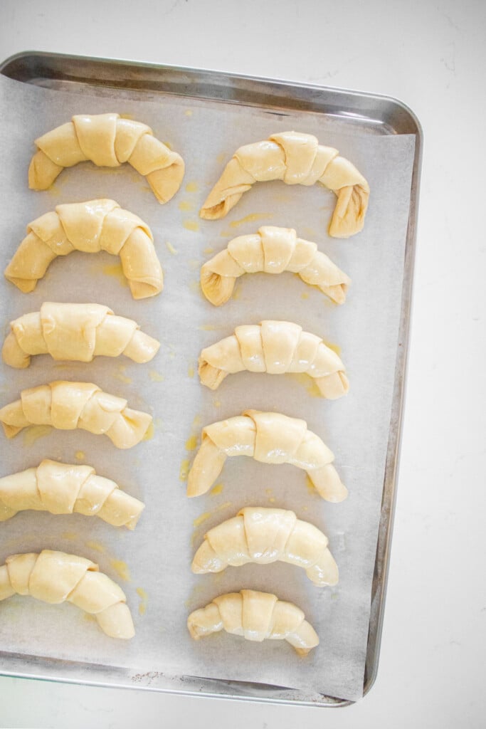 sourdough crescent rolls brushed with egg wash on a baking sheet.