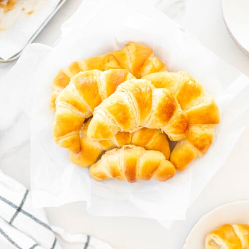 sourdough crescent rolls on a plate on a white marble countertop.