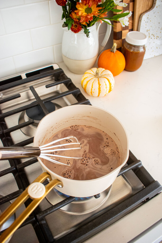 hot cocoa being whisked together over the stovetop in a small pot.