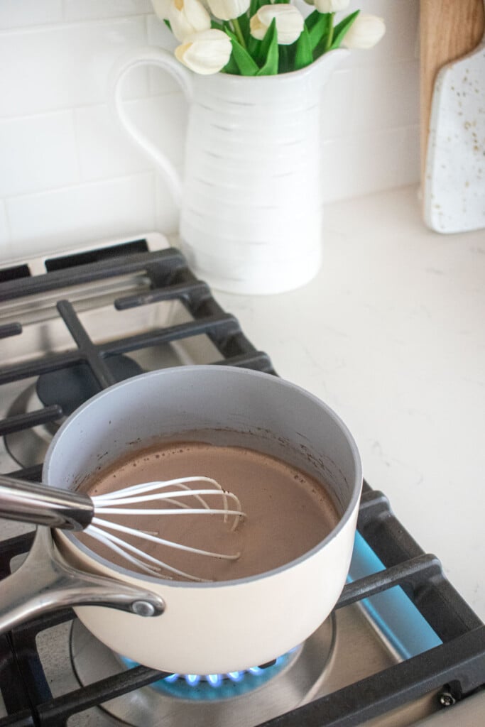 hot cocoa being stirred in a small pot on the stovetop.