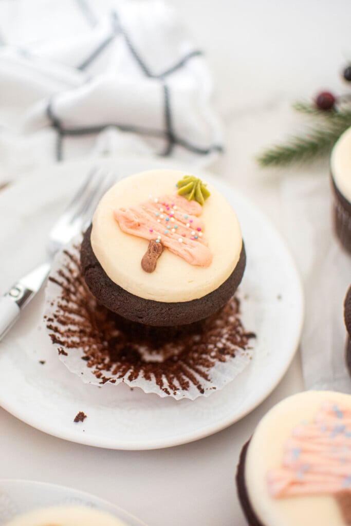 chocolate peppermint cupcakes with a pink buttercream christmas tree on top on a plate.