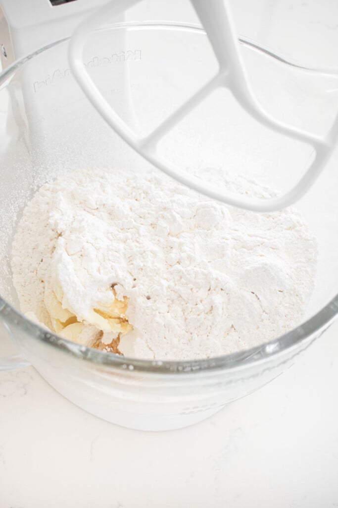 ingredients for eggnog frosting in a glass mixing bowl on a marble counter.