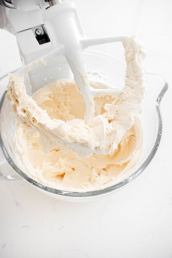 eggnog frosting in a glass mixing bowl on a marble counter.