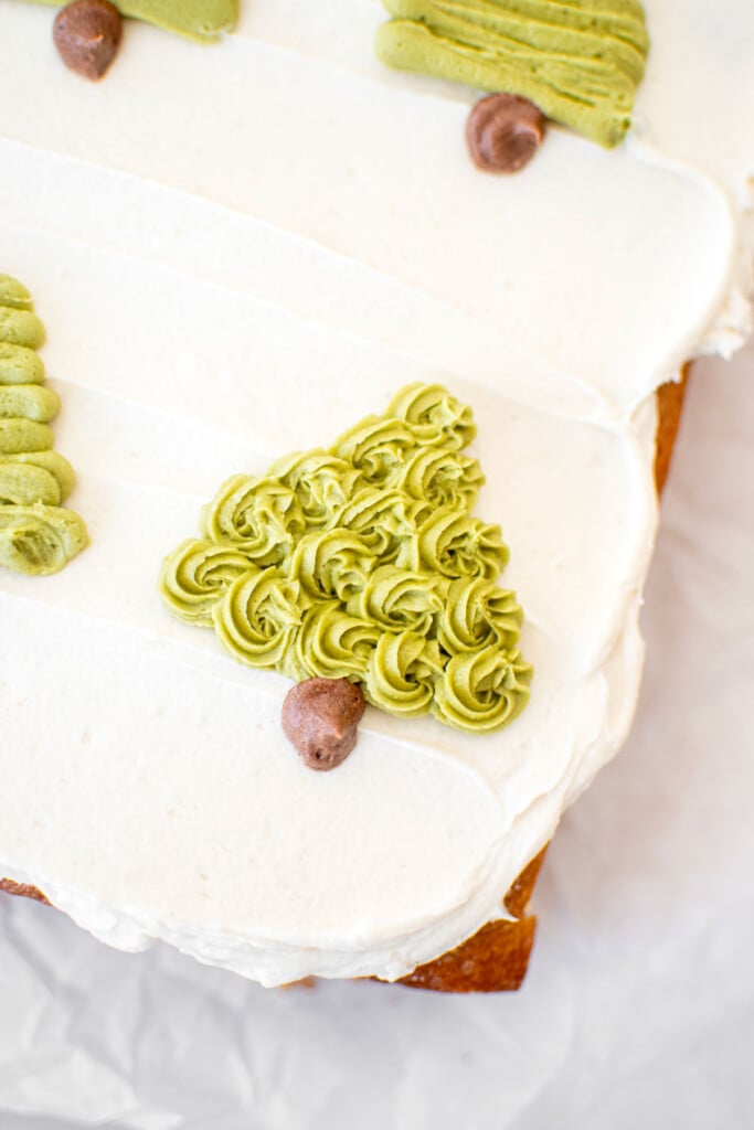 buttercream christmas trees piped onto a sheet cake on top of white frosting.