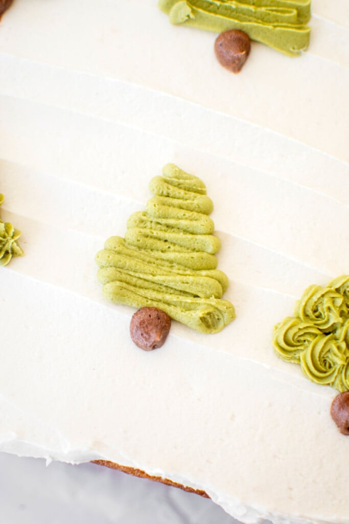 buttercream christmas trees piped onto a sheet cake on top of white frosting.