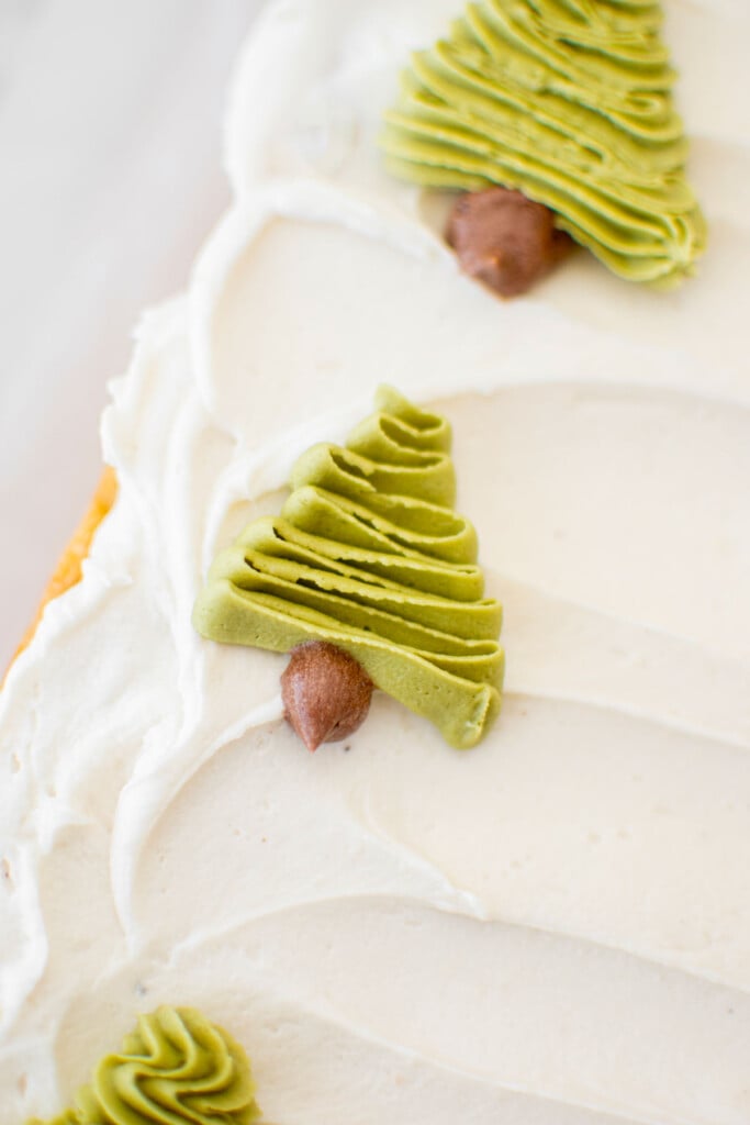 buttercream christmas trees piped onto a sheet cake on top of white frosting.