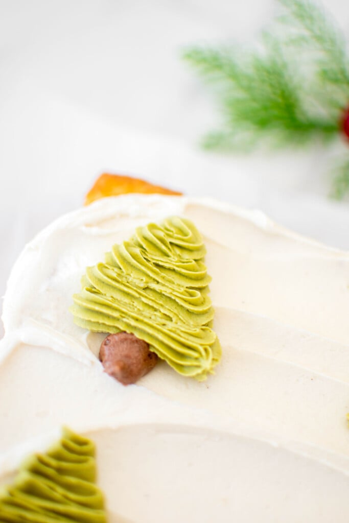 buttercream christmas trees piped onto a sheet cake on top of white frosting.