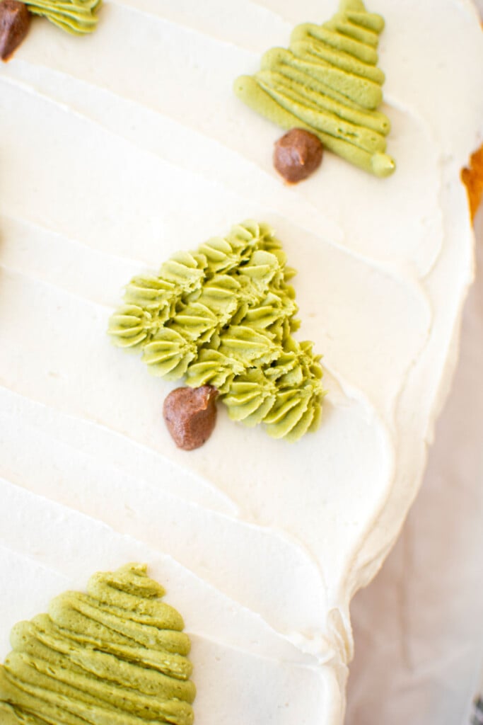 buttercream christmas trees piped onto a sheet cake on top of white frosting.