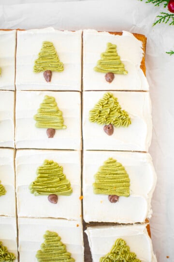 eggnog sheet cake with green buttercream trees piped onto each slice on a white marble counter.