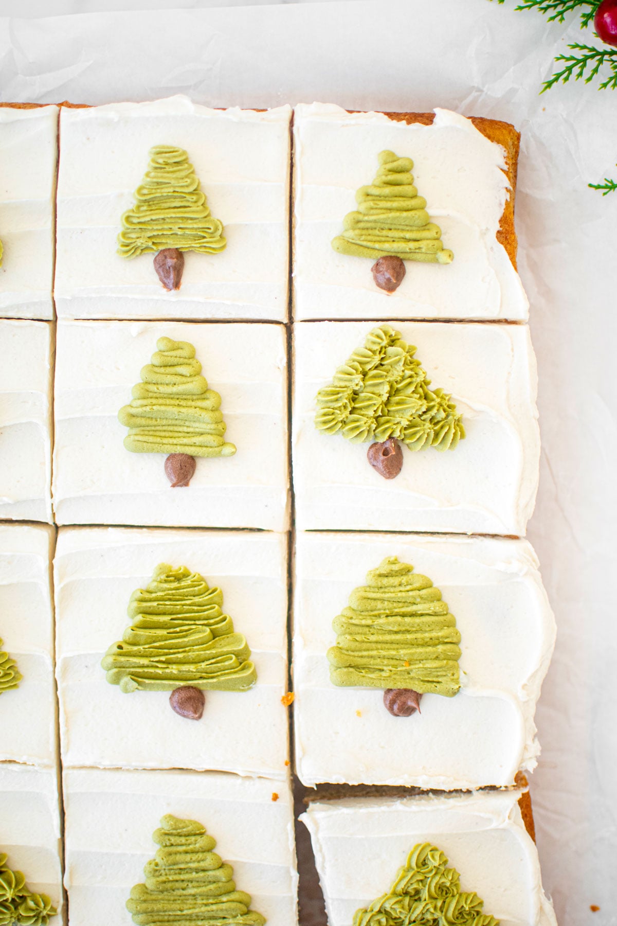 eggnog sheet cake with green buttercream trees piped onto each slice on a white marble counter.