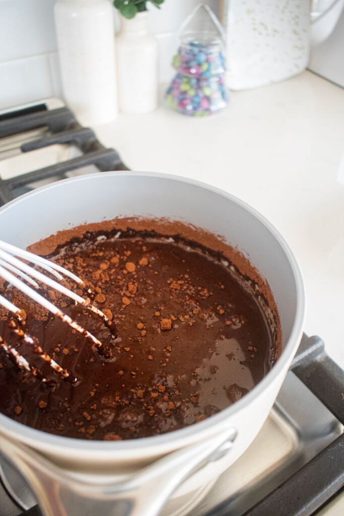bone broth hot cocoa being stirred with a whisk over the stovetop.