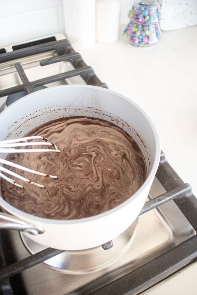 bone broth hot cocoa being stirred with a whisk over the stovetop.
