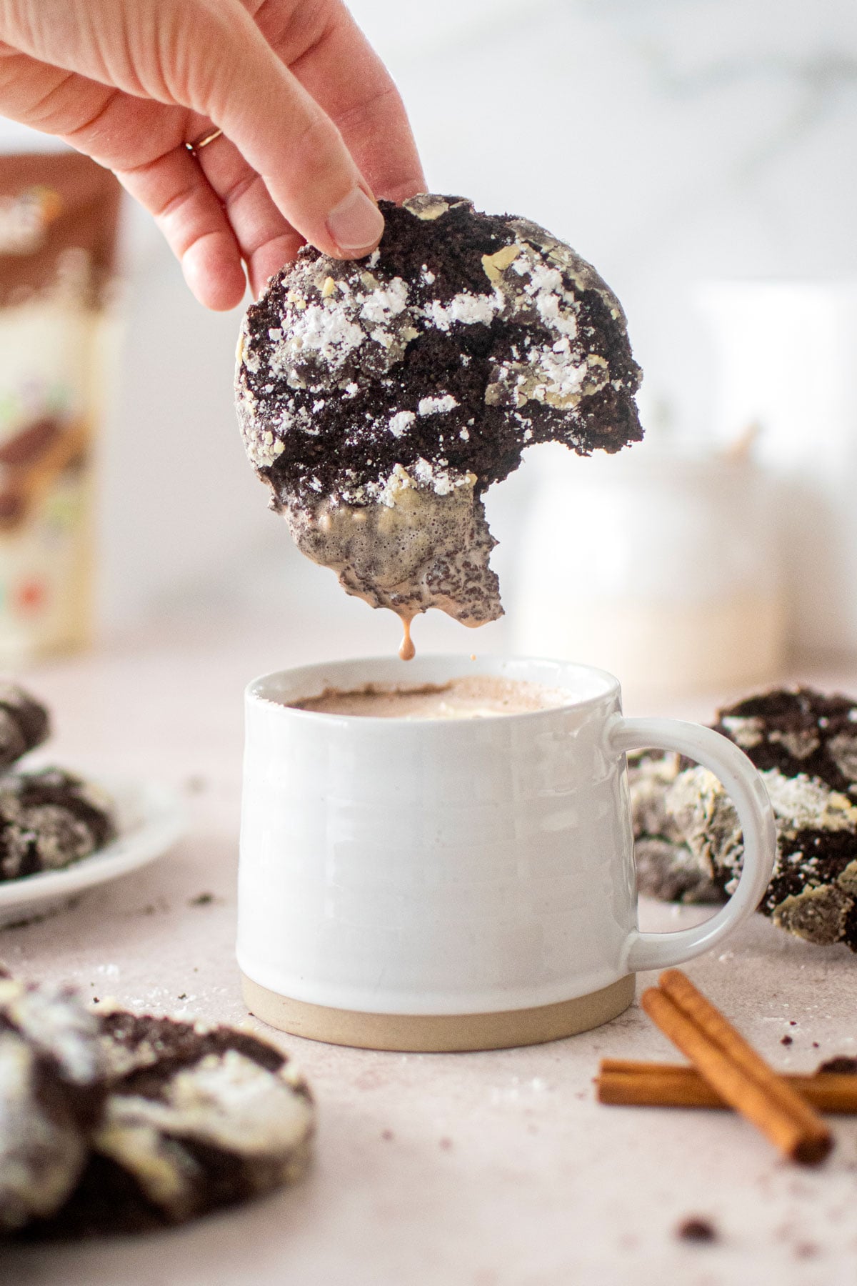 woman dipping mexican hot chocolate crinkle cookie in a hot cocoa.