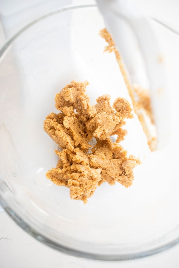 creamed butter and sugar in a glass mixing bowl on a white marble counter.