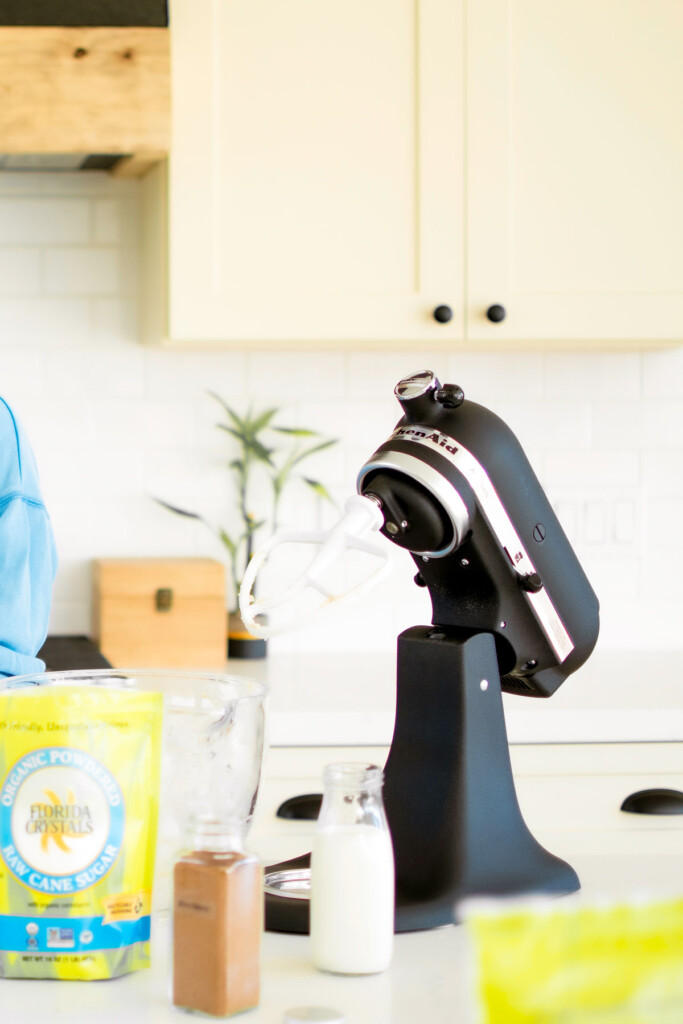 black stand mixer with baking supplies on kitchen counter.
