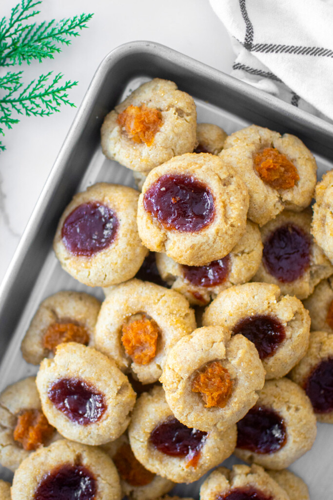 sourdough jam thumbprint cookies on a baking sheet on a marble counter.