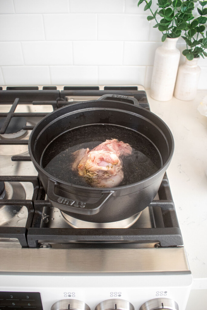 ham bone in water in a dutch oven on a stovetop.