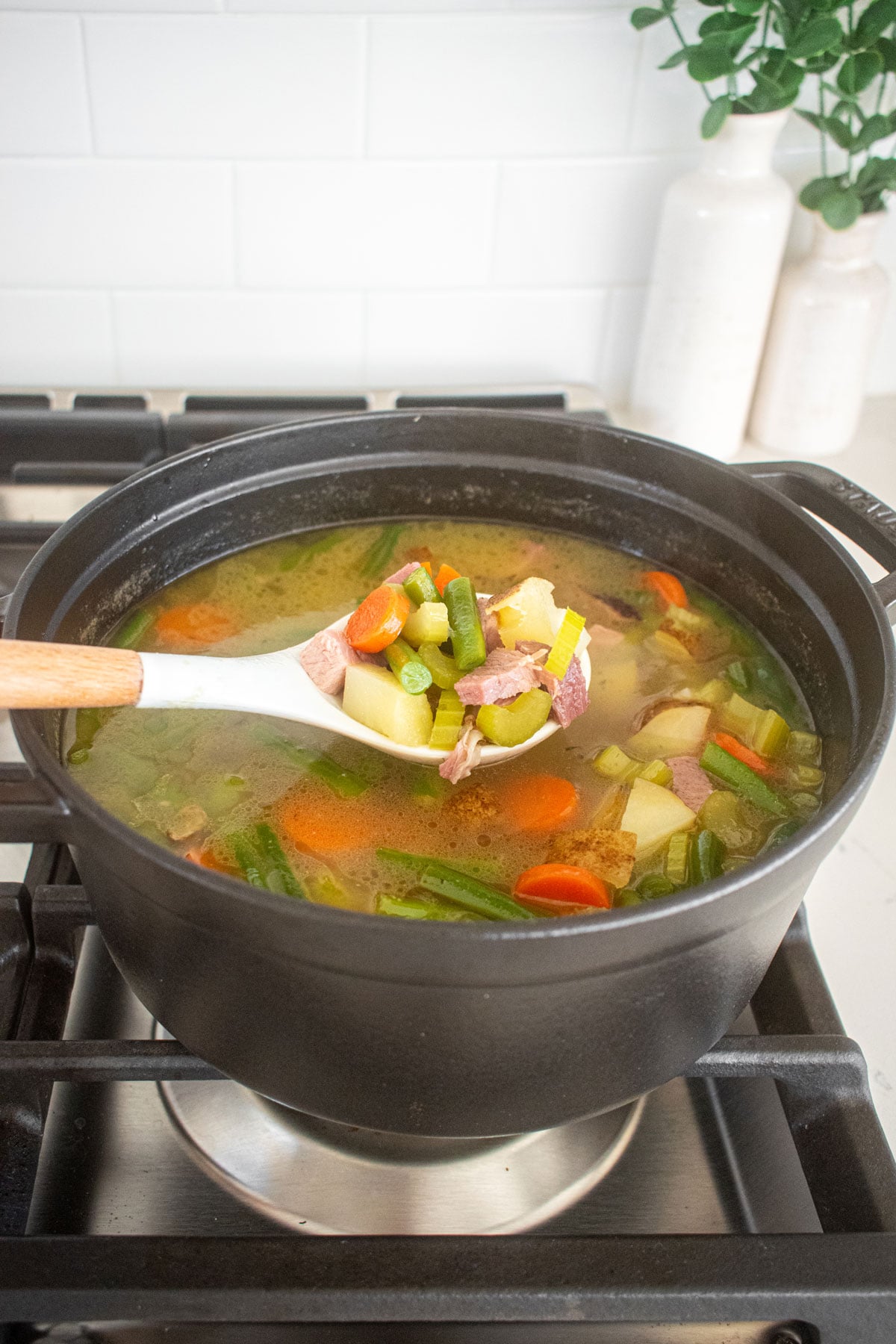 ham bone soup simmering in a dutch oven on a stovetop.
