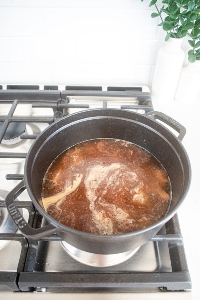 beef with bone broth in a black dutch oven on the stovetop.