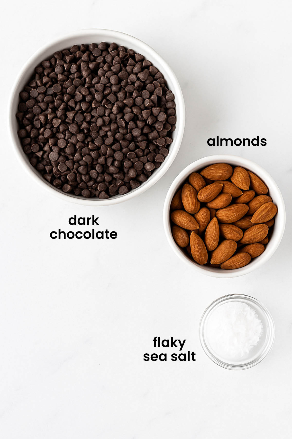 individual ingredients for salted almond dark chocolate bars laid out against a white background.