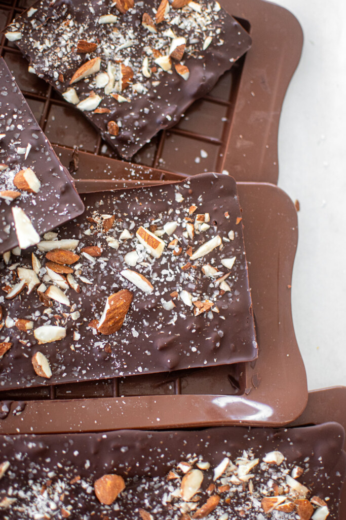 salted almond dark chocolate bars being taken out of chocolate molds.