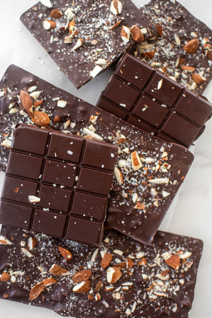 salted almond dark chocolate bars on a white marble counter.