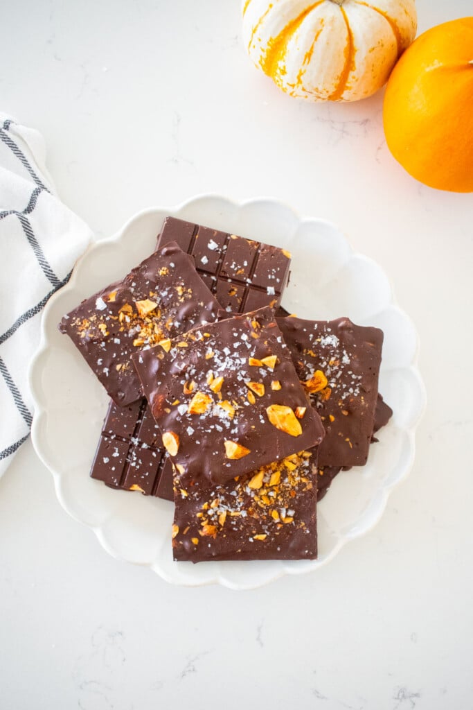 salted almond dark chocolate bars on a plate on a marble counter with tiny pumpkins.