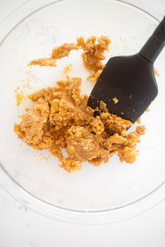 single serve cookie dough in a glass mixing bowl on a marble counter with a spatula.