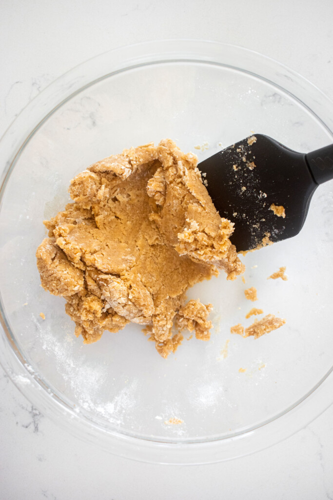 single serve cookie dough in a glass mixing bowl on a marble counter with a spatula.