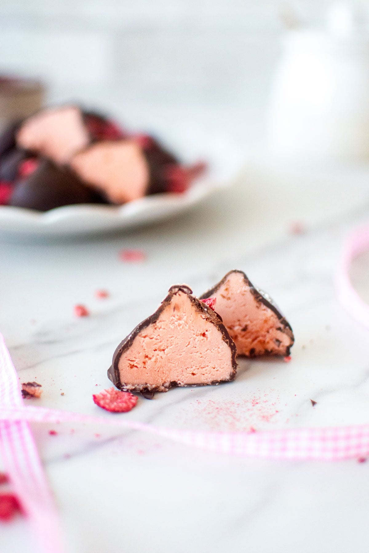 strawberry cream drop cut in half to reveal strawberry center on a white marble counter.